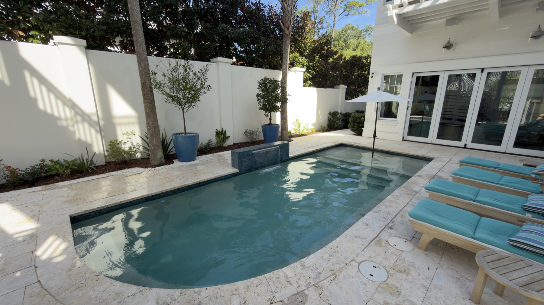Courtyard pool with a water feature and travertine deck in Santa Rosa Beach, serviced by WittCo Pools