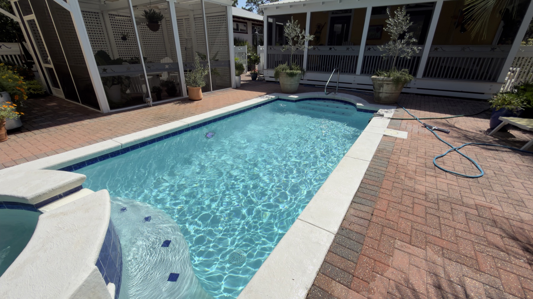 Pool and attached spa with clear blue water on a brick paver deck in Miramar Beach, Florida